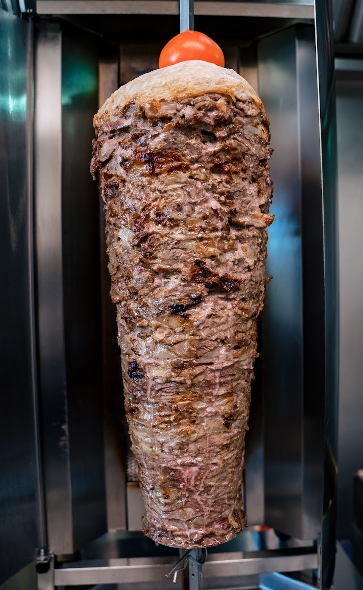 Beef shawarma slow-roasting on a vertical spit